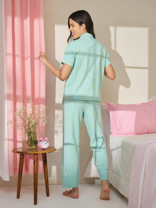 A woman playfully poses in a light blue pajama set with a yellow floral print.