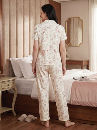 Woman in cream-colored pajamas with a playful red dog print, posing from the back.