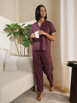 Woman in a deep maroon printed sleepwear set, holding a mug.