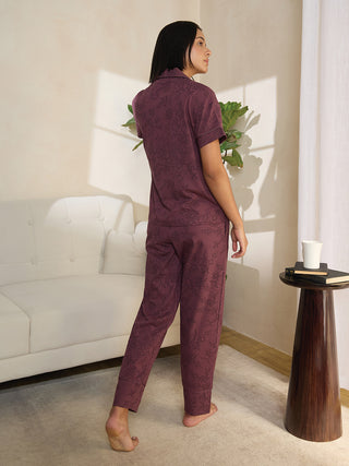A woman in maroon floral print pajamas stands facing away from the camera, her head turned to the side.