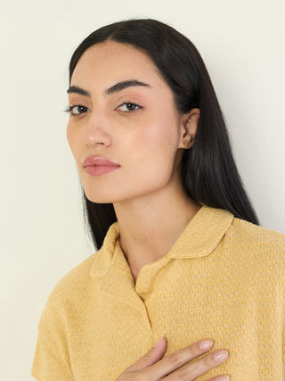 A woman wears a yellow collared sleep shirt.