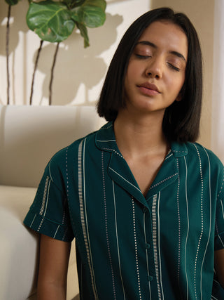 A woman with closed eyes wears a dark green pajama top with a vertical stripe print.