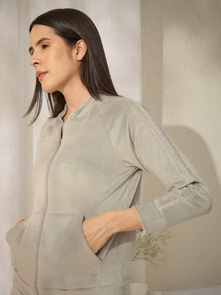 Women in a grey velour tracksuit with lace trim on the sleeves.