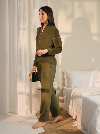 A woman in a green fleece pajama set poses with a book in a bedroom setting.