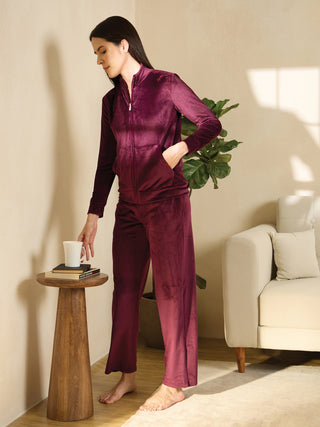 Women in a relaxed pose, wearing a burgundy velvet tracksuit.