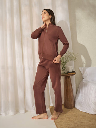 Women in a casual pose wearing a brown zippered tracksuit.