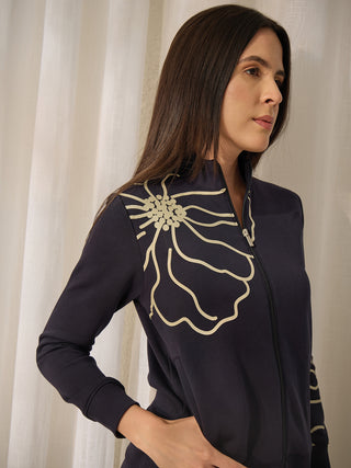 A woman wearing a dark navy zippered sweatshirt with a cream floral print.