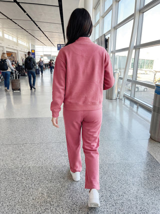A woman walks away from the camera wearing a rose pink loungewear set.