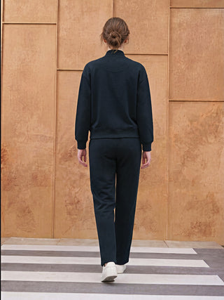 A woman wearing a navy blue loungewear set, with her back to the camera, walks on a striped walkway.