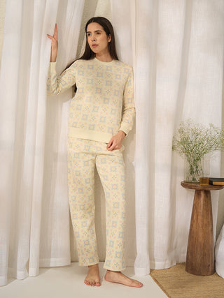 Women in a relaxed pose wear a pale yellow pajama set with a delicate floral print.
