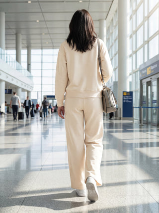 Woman from behind wearing a light beige loungewear set, with a shoulder bag.