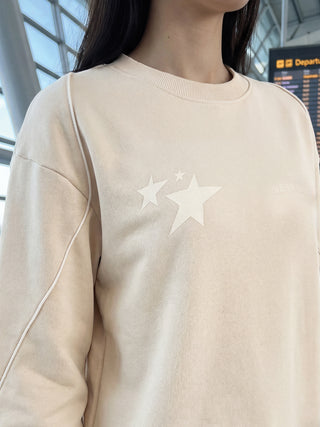Woman wearing a light beige sweatshirt with star prints.