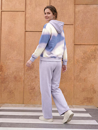 A woman is posing in a tie-dye hoodie and matching sweatpants.