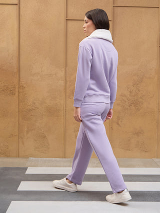 Women walking across a crosswalk in a light purple sweat suit with a white fuzzy collar.