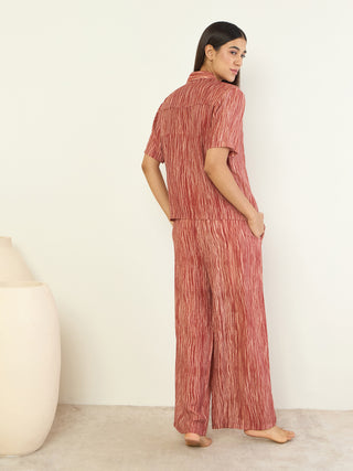 Women in a rust-colored, vertically striped matching sleep set, posed looking over her shoulder.