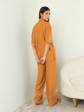 Women's orange printed sleepwear set with wide-leg pants and a collared top.
