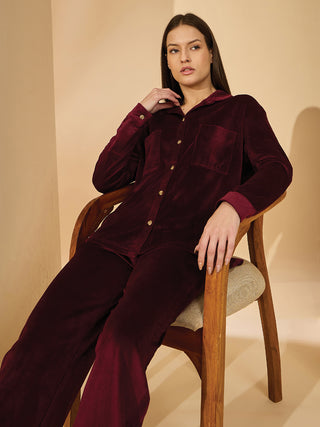 Women in a reclined pose, wearing a burgundy corduroy pajama set.