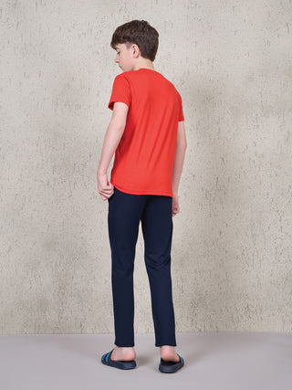 BOYS in a rear view, wearing a red t-shirt and navy blue pants.