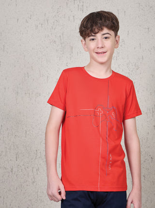 BOYS wearing a red t-shirt with a controller graphic and navy blue shorts, posing in front of a textured wall.