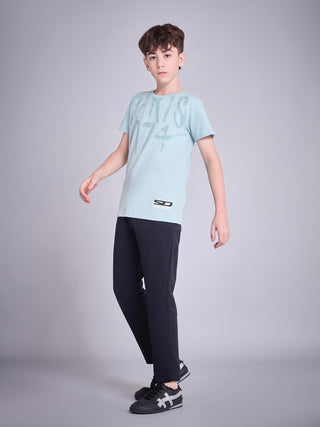BOYS wearing a light blue t-shirt with a faded print and black pants.