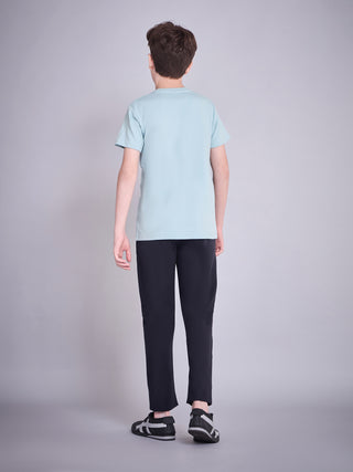 BOYS, from behind, wearing a light blue t-shirt and navy blue pants with black and white sneakers.