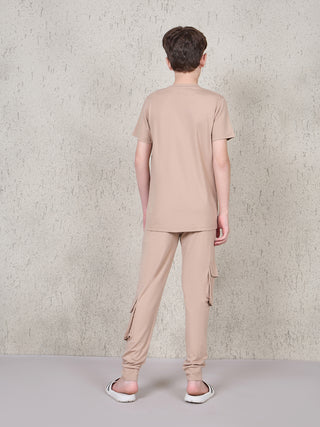 BOYS back view of a boy in beige t-shirt and beige cargo pants with slide sandals.