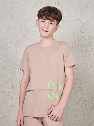 Boy standing front-facing wearing a beige short-sleeve sleepwear set with matching bottoms and neon green SD graphic print on the T-shirt.