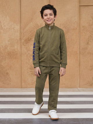 A boy stands wearing a green zip-up jacket with blue "SKATER" print and matching green pants.