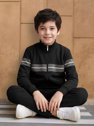 BOYS sitting cross-legged wearing a black tracksuit with grey stripes, a slight variation from the other loungewear images.