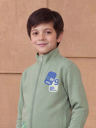 BOYS wearing a light green zip-up jacket with a graphic print on the chest, featuring a ticket-like design with "X 89 9 SO MOVE" and "JUST SOME ROAM AROUND" text.