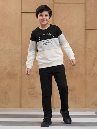 Boy wearing a color-blocked sweatshirt with "Los Angeles California" print and black pants.