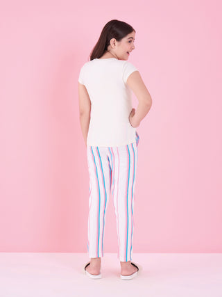 Girl standing in a back-facing pose against a pink backdrop, wearing a swan white short-sleeve pyjama set with full-length pants in pink, teal and blue vertical stripe print.