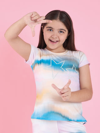 Girls in a tie-dye pajama set with star print smile and make a frame with their hands.
