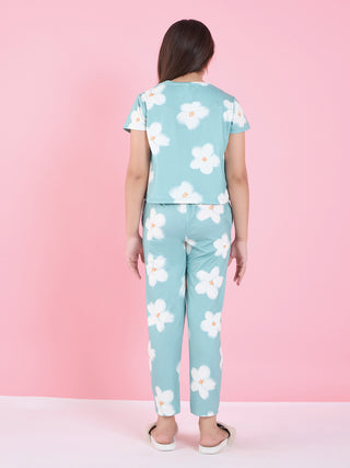Girls in a light blue pajama set with white floral print, facing away from the camera, wearing slippers.