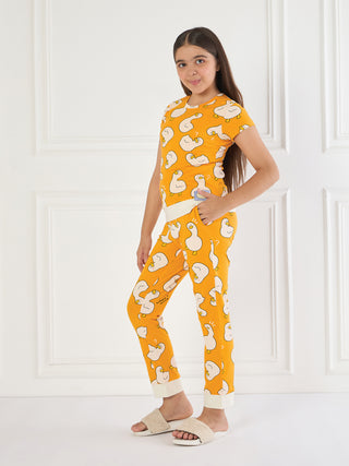 Girl in orange pajamas with a duck print, standing with her hand in her pocket.