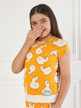 Girls, a medium shot, wearing an orange short-sleeved shirt with a white duck print and a cream waistband.