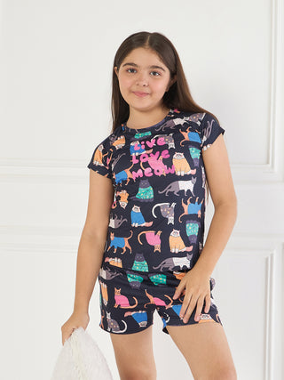 GIRLS dark blue pajama set with a repeating pattern of cats and the words "Live Love Meow", in a standing pose, smiling at the camera.