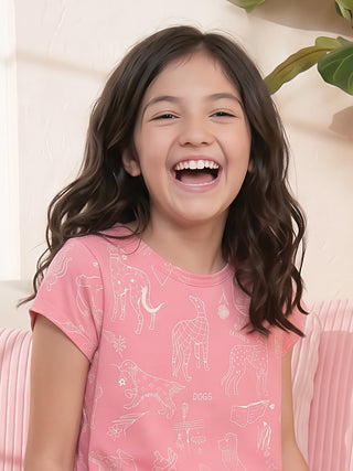 Girls, a joyful girl with her hair flowing backward is wearing a pink short-sleeved top with white cartoon dog prints, a cozy and playful addition to their sleepwear collection.