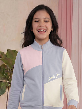 Girls' color-blocked zip-up jacket in pastel pink, blue, and cream with "Little Joy" embroidery.
