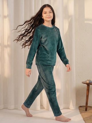 Girls in a teal velvet pajama set with embroidered bows on the top, walking.
