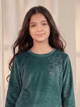 Girls in a teal velour pajama top with two white bow prints.