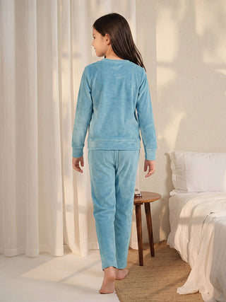 Girls in light blue velour pajamas stand facing away from the camera.