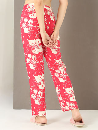 A woman in pink floral pajamas, standing with hands behind her back.