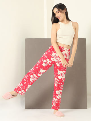 Woman in pink floral pajama pants and a cream tank top, posing playfully with one leg extended.