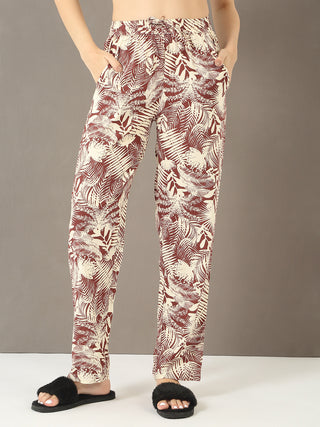 Women posing in cream and maroon tropical print pajama pants and black fuzzy slippers.