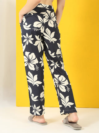 Women's dark blue floral print pajama pants with a white hibiscus pattern, styled with grey slippers.