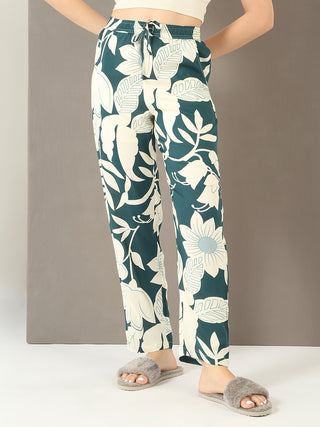 Women are posing in a white bralette and teal floral print pajama pants, with grey fuzzy slippers.