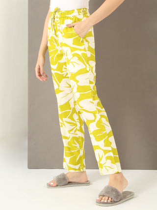 Women's lime green and white floral print lounge pants with grey fur slippers.