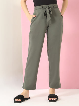 Women wearing olive green drawstring pants and black fuzzy slippers, shown from the waist down against a pink and white backdrop.
