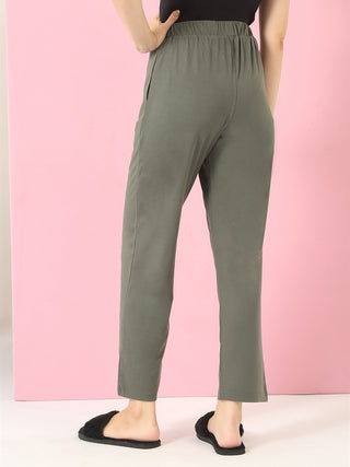 Women wearing olive green sleepwear pants and black fuzzy slippers, standing with hands on hips.